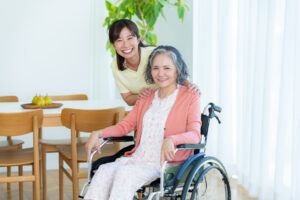 車いすに乗った高齢者と介護スタッフがこちらを見ている様子